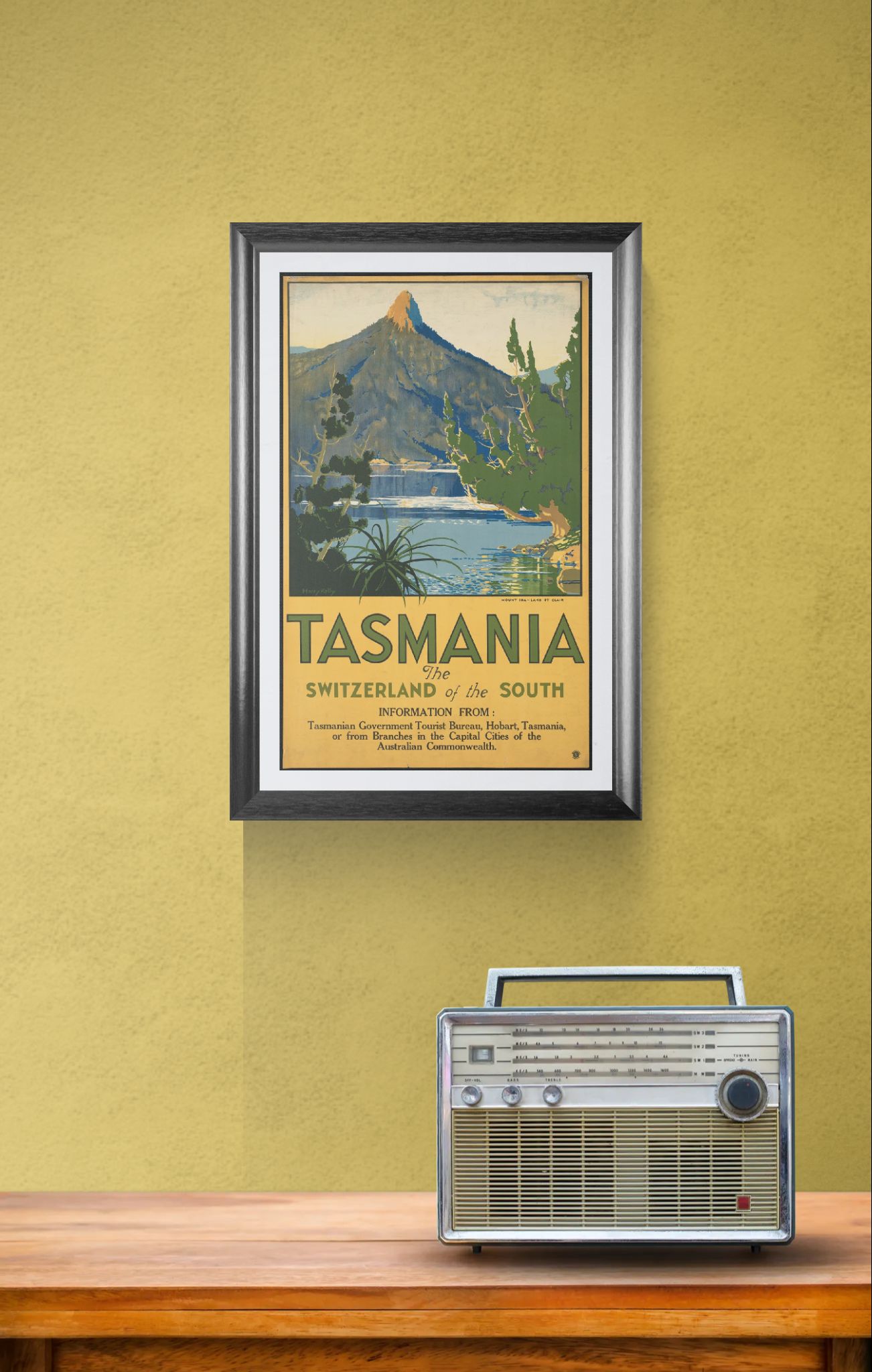Framed Tasmania travel poster on a wall above a wooden surface with a vintage radio.