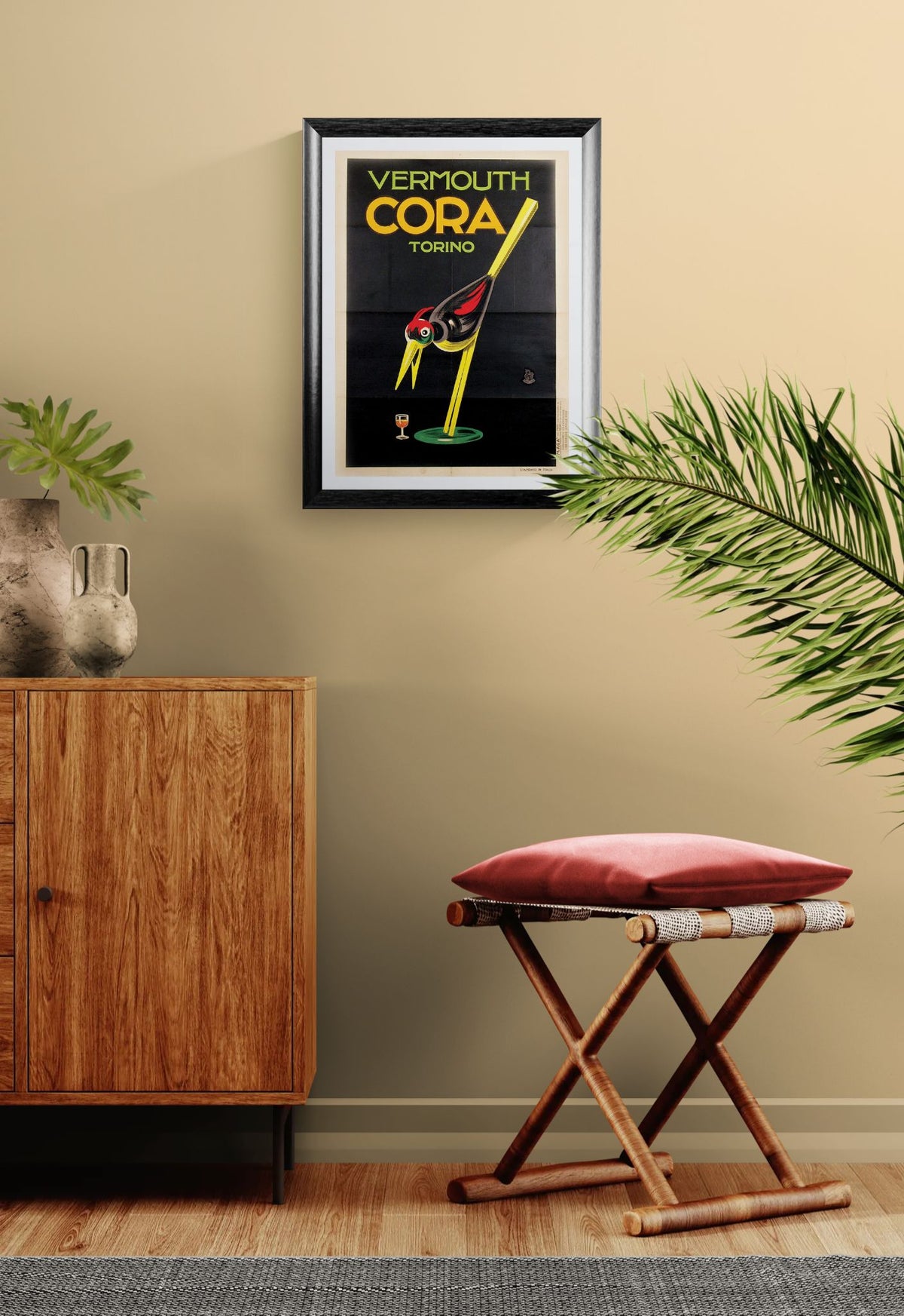 Framed Cora Vermouth advertisement on a wall with a wooden cabinet and stool in a room.