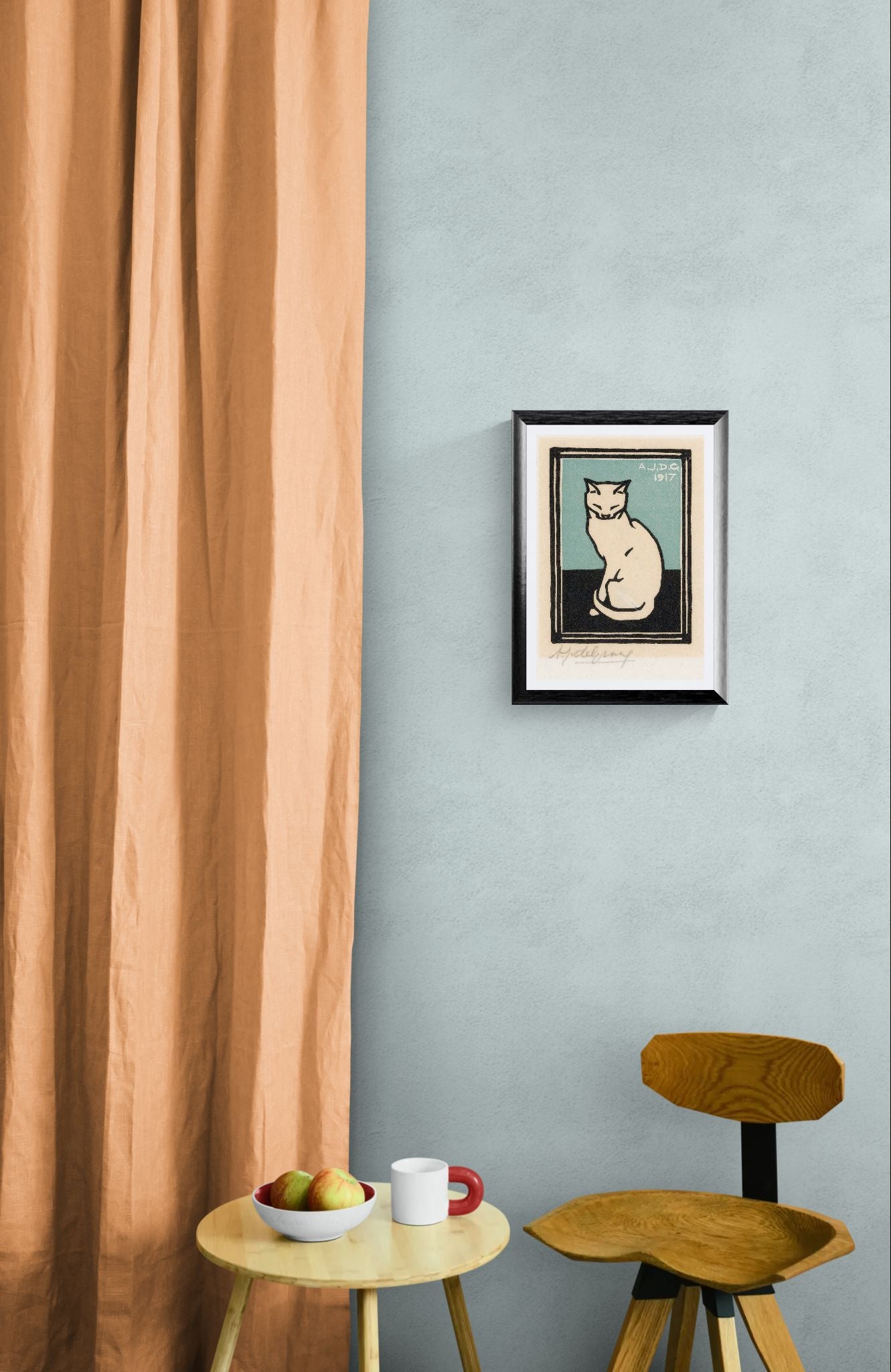 Framed picture of a cat on a light blue wall with a wooden chair and small table below.