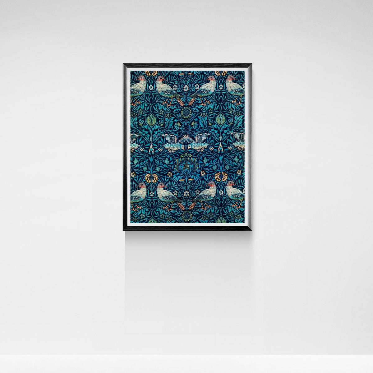 Framed artwork with a blue pattern featuring birds and flowers on a white wall.