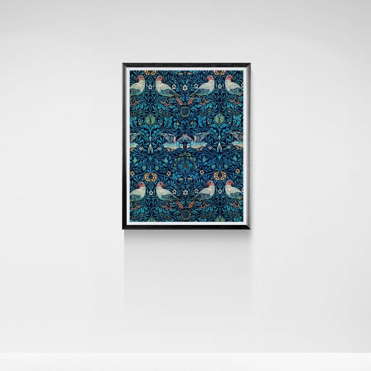 Framed artwork with a blue pattern featuring birds and flowers on a white wall.