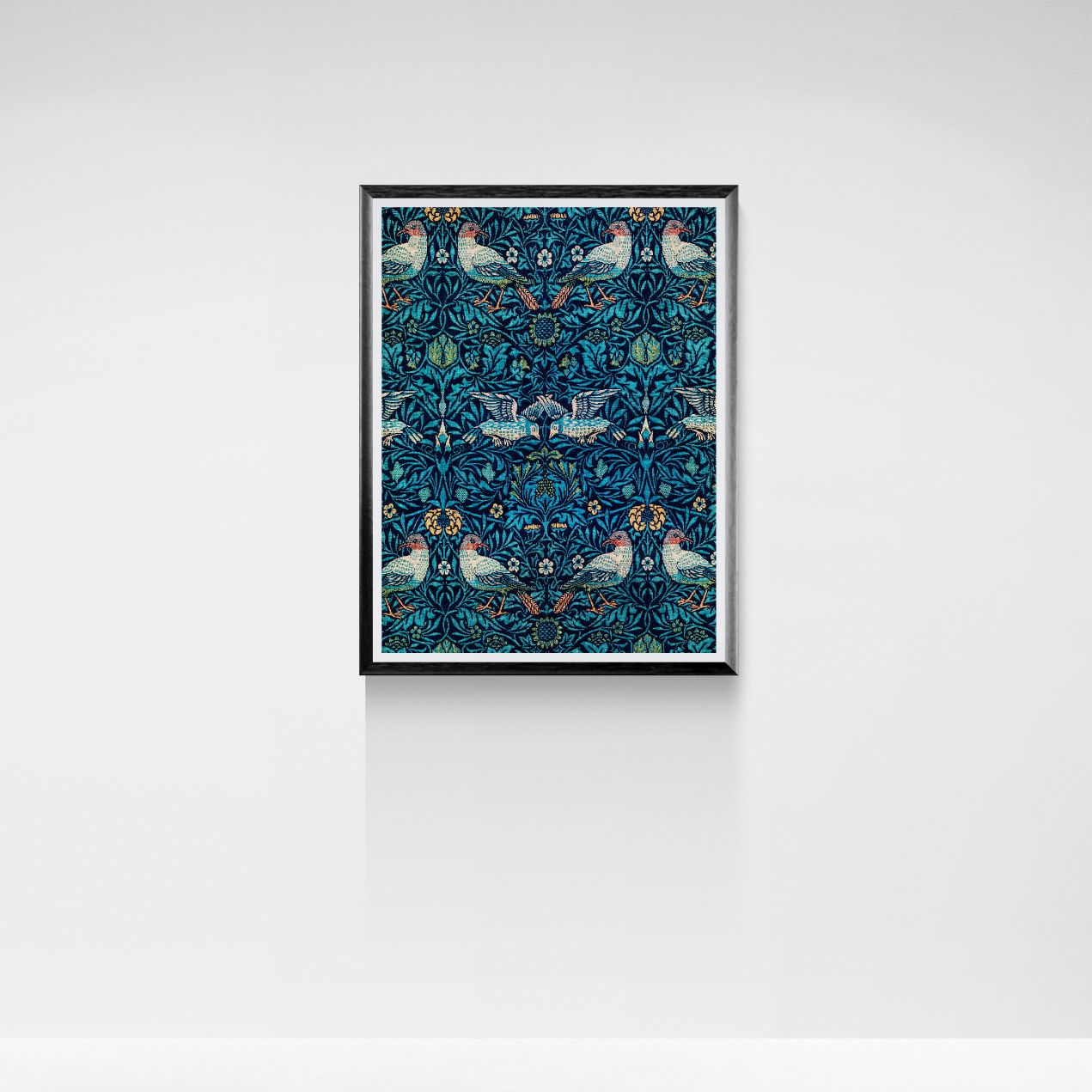 Framed artwork with a blue pattern featuring birds and flowers on a white wall.