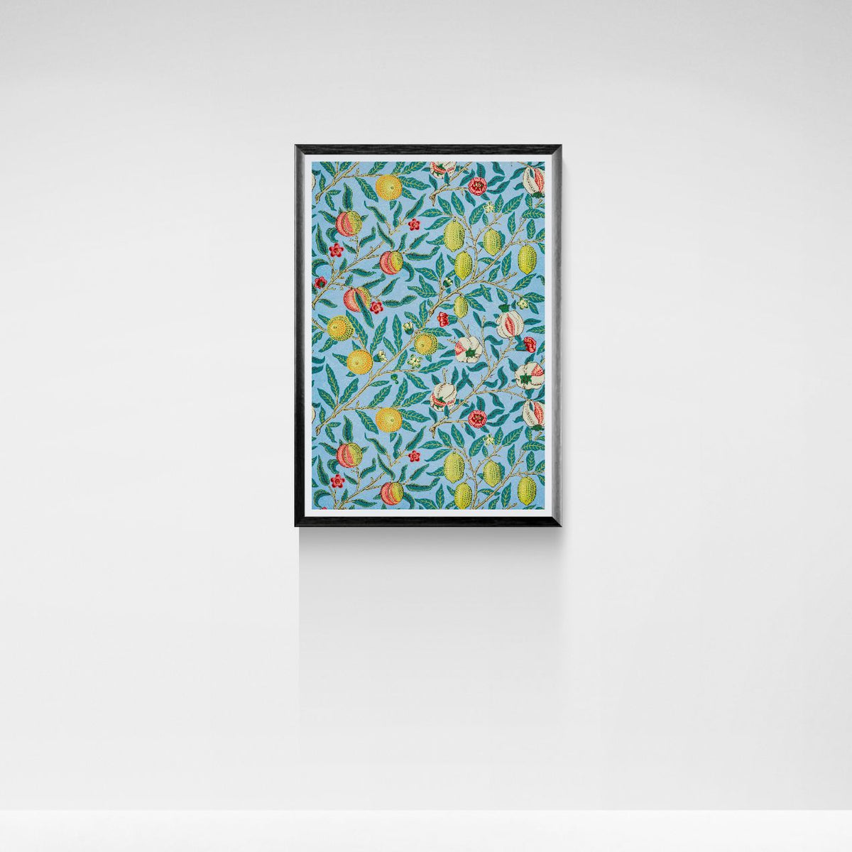 Framed artwork with a colorful pattern of fruits and leaves on a white wall.