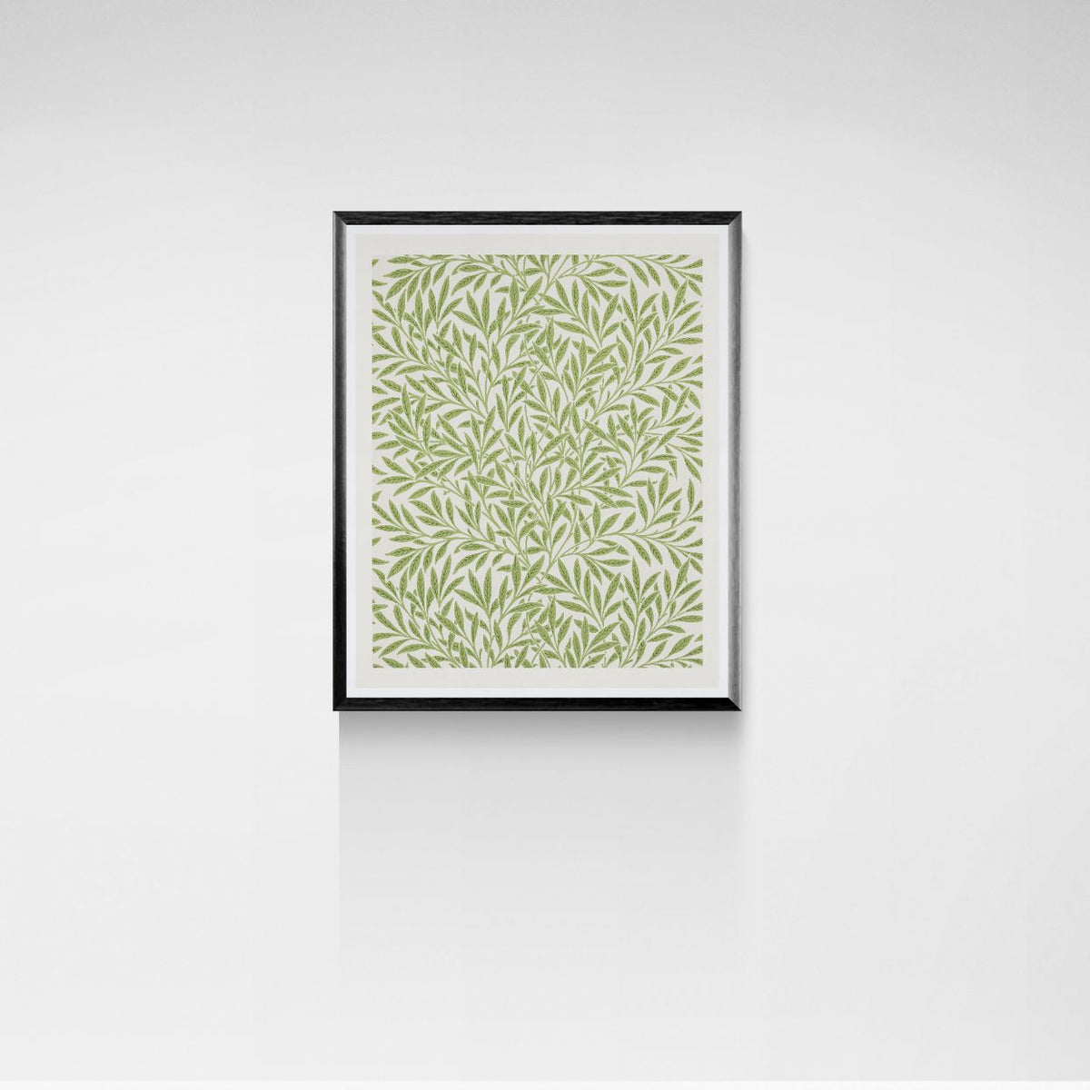 Framed artwork with a green leaf pattern on a white wall