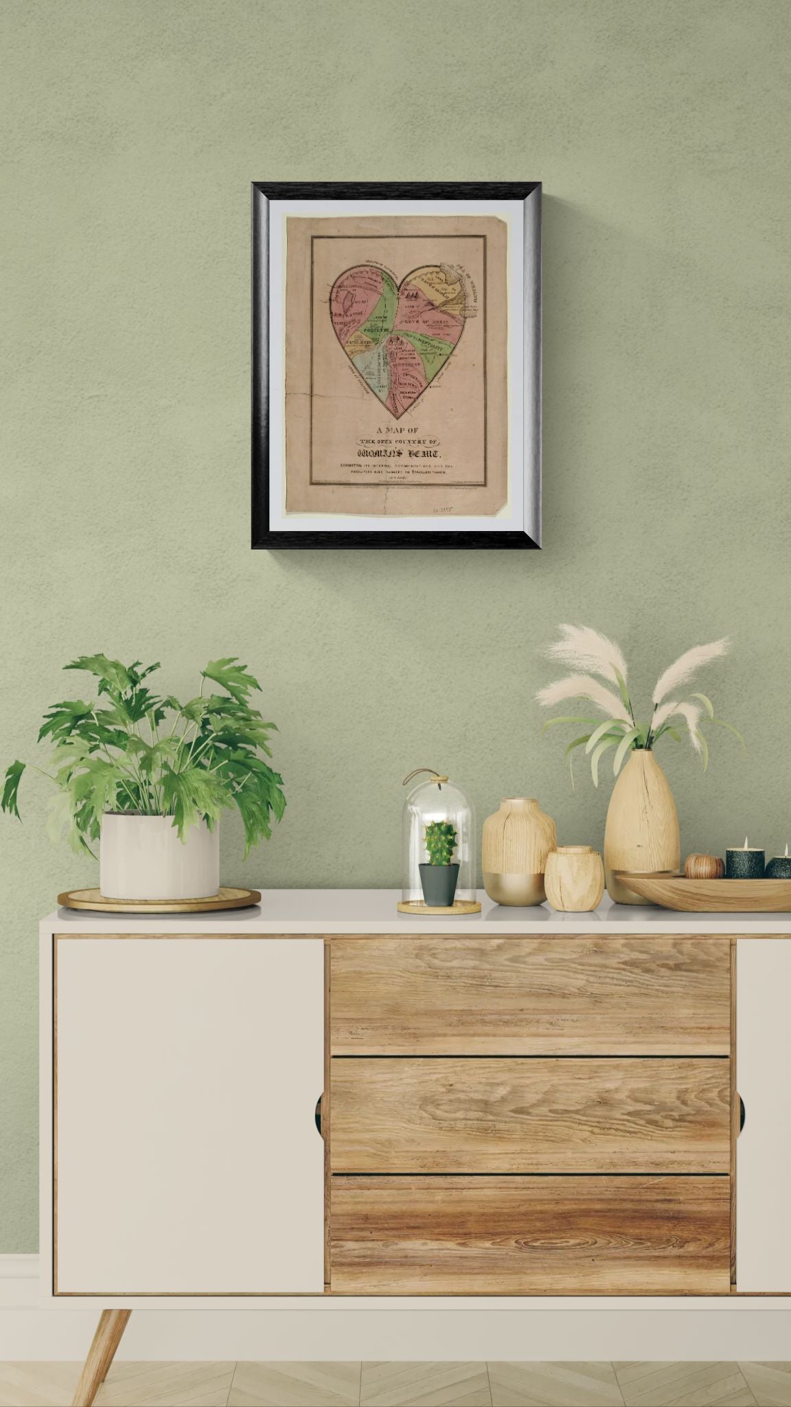 Wooden sideboard with decorative items against a green wall with framed artwork.
